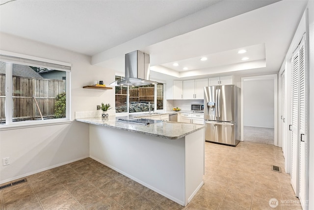 kitchen with visible vents, a sink, a tray ceiling, stainless steel appliances, and island range hood