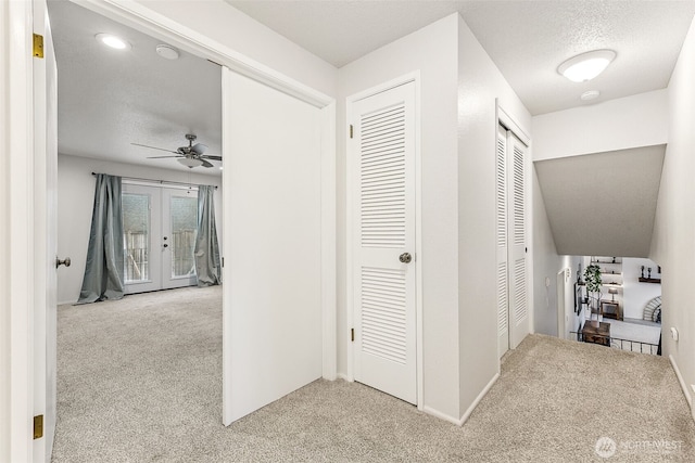 hall with baseboards, french doors, a textured ceiling, and carpet