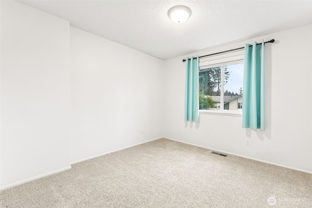 unfurnished room with carpet flooring, baseboards, visible vents, and a textured ceiling