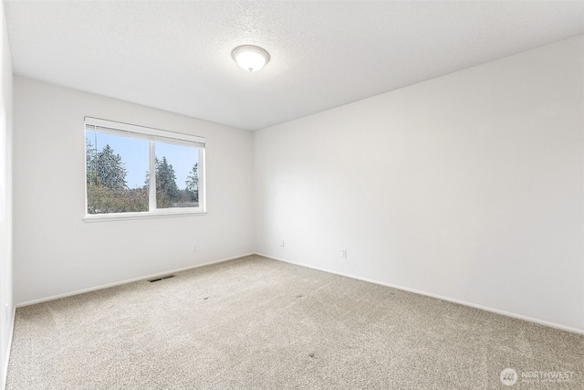 empty room featuring visible vents, baseboards, a textured ceiling, and carpet flooring