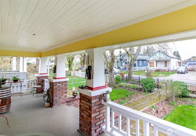 view of patio with fence, covered porch, and a residential view