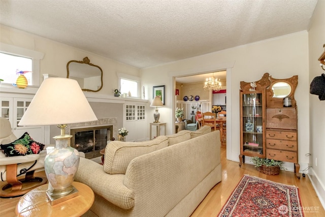 2029 S 7th St, Tacoma, WA 98405 - living room with a glass covered fireplace, a textured ceiling, light wood-type flooring, and an inviting chandelier