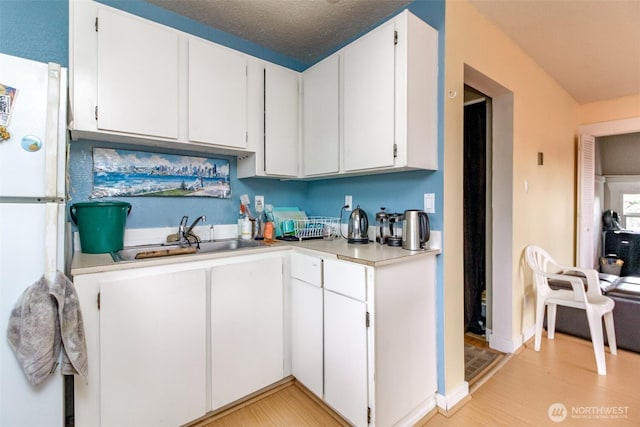 2029 S 7th St, Tacoma, WA 98405 - kitchen featuring freestanding refrigerator, a sink, light countertops, white cabinets, and a textured ceiling