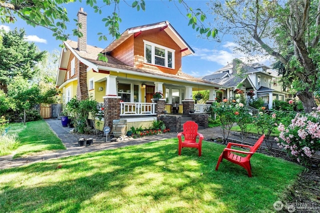 rear view of house featuring a yard, a porch, a chimney, and fence