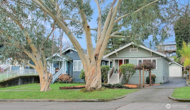 view of front of home featuring a front yard, an outbuilding, fence, driveway, and a detached garage