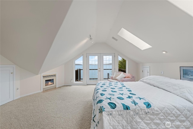 carpeted bedroom with visible vents, lofted ceiling with skylight, access to outside, a glass covered fireplace, and baseboards