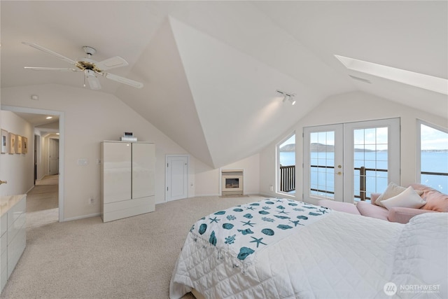 bedroom featuring baseboards, light carpet, vaulted ceiling with skylight, french doors, and access to outside