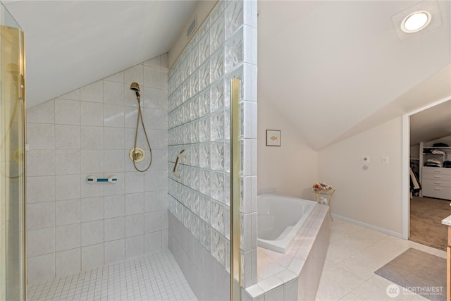 bathroom featuring a shower stall, a walk in closet, baseboards, a garden tub, and lofted ceiling