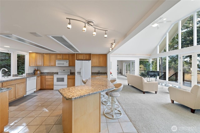 kitchen with open floor plan, light tile patterned floors, light carpet, white appliances, and a sink