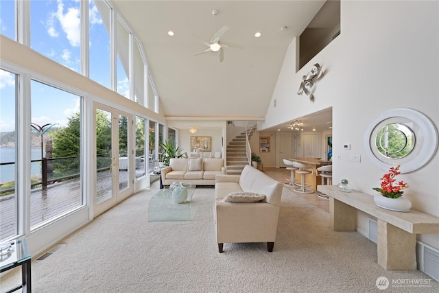 carpeted living area featuring stairway, a ceiling fan, visible vents, recessed lighting, and a towering ceiling