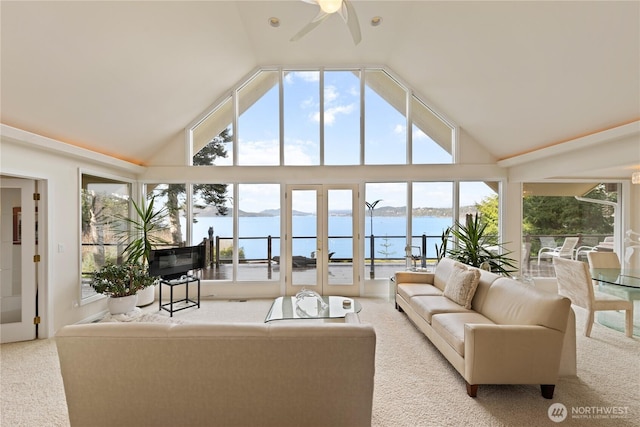 carpeted living room featuring high vaulted ceiling, a ceiling fan, and a water view