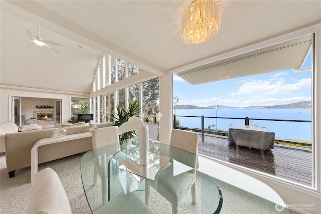 sunroom featuring vaulted ceiling, plenty of natural light, a water view, and a lit fireplace