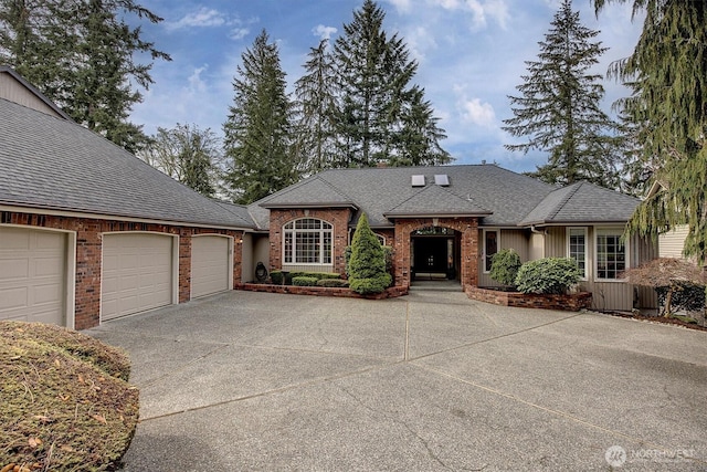 view of front of home featuring a garage, brick siding, driveway, and roof with shingles