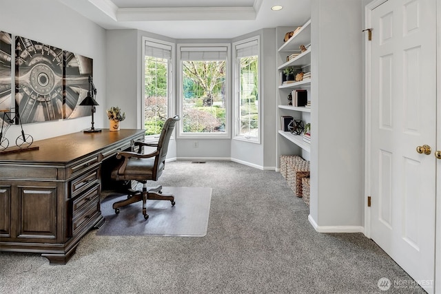 carpeted office space with baseboards and a raised ceiling