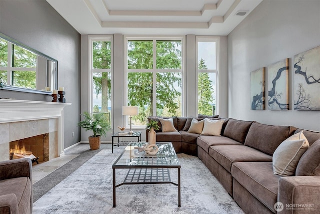 living room with a raised ceiling, a healthy amount of sunlight, and a high end fireplace