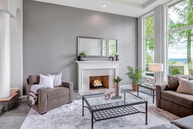 living room featuring decorative columns, plenty of natural light, baseboards, and a tile fireplace