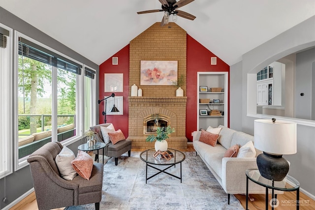 living room with light wood-style flooring, built in features, a fireplace, baseboards, and vaulted ceiling