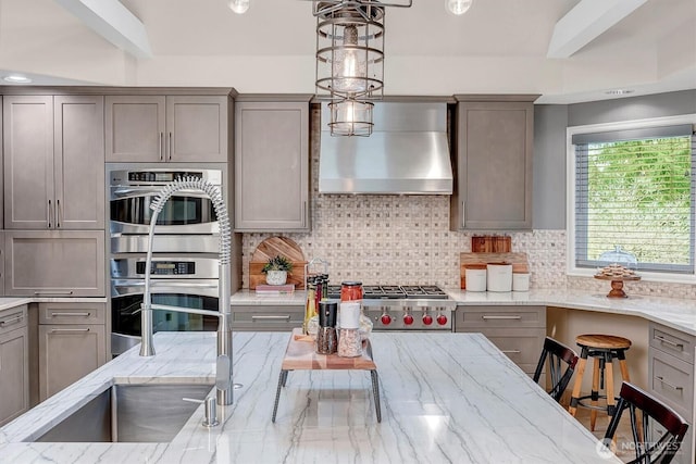 kitchen with a sink, wall chimney range hood, gray cabinets, and stainless steel double oven