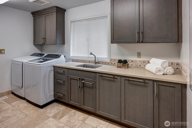 washroom featuring washing machine and dryer, cabinet space, visible vents, and a sink