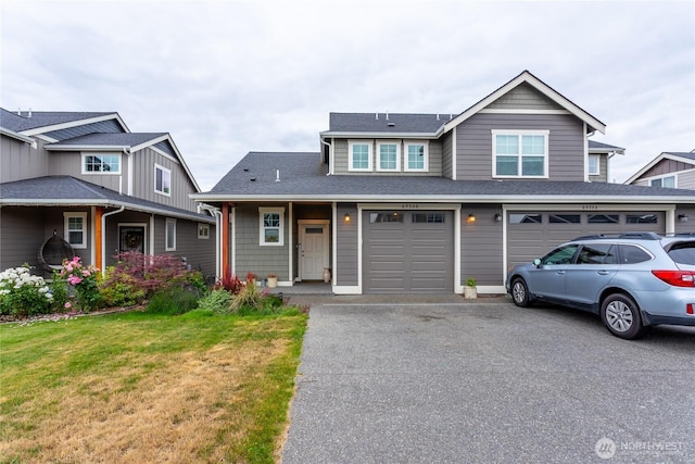 view of front facade featuring a front yard, an attached garage, driveway, and roof with shingles