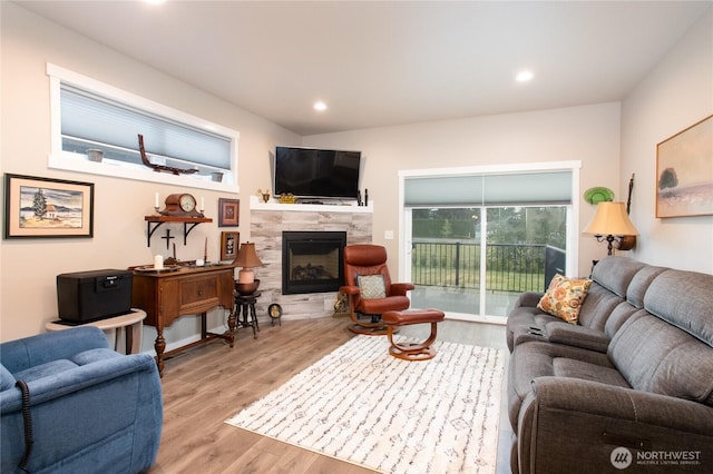 living room with recessed lighting, a tile fireplace, and light wood-style floors