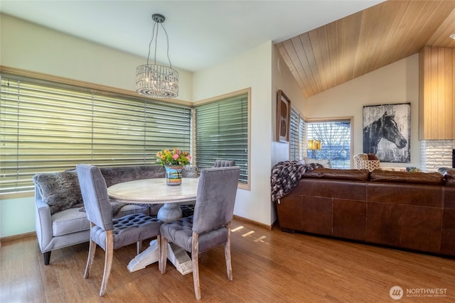 dining area featuring baseboards, a notable chandelier, wood finished floors, and vaulted ceiling