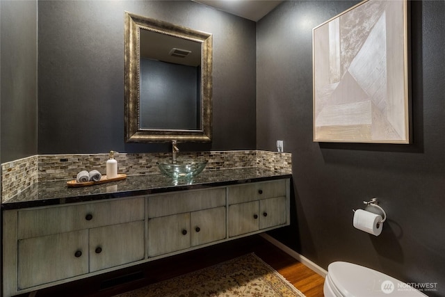 bathroom featuring visible vents, toilet, wood finished floors, baseboards, and vanity