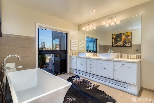 full bath with a freestanding bath, double vanity, tile patterned flooring, and a sink