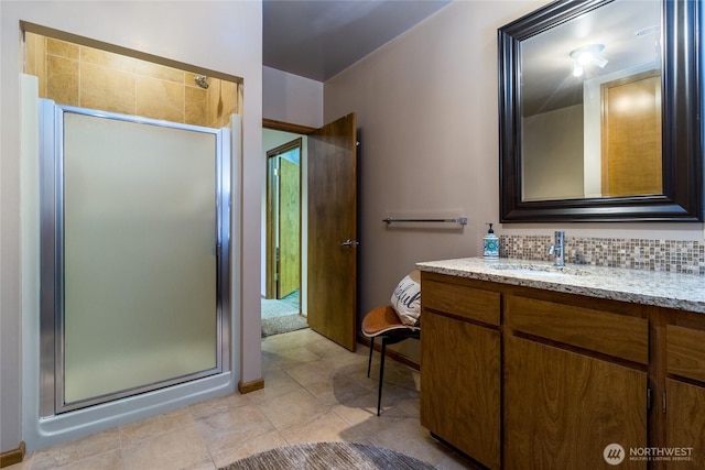 bathroom featuring tasteful backsplash, a shower stall, tile patterned floors, and vanity