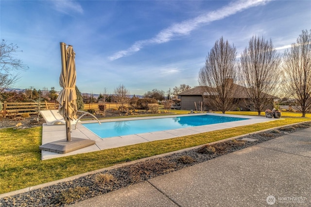 pool with an outdoor structure, a yard, and fence