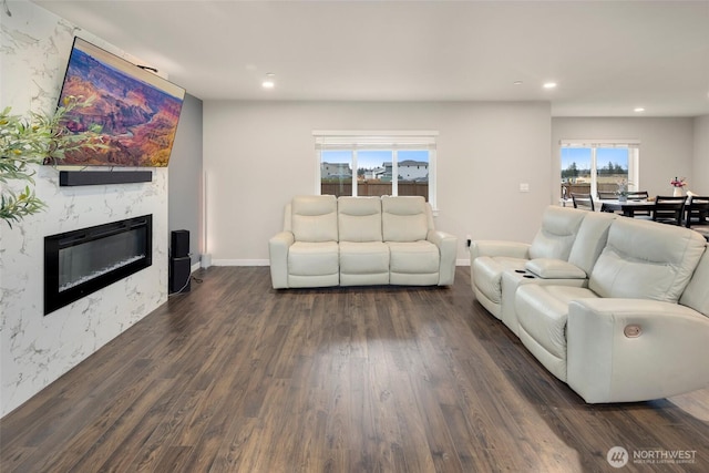 living area featuring a premium fireplace, recessed lighting, baseboards, and dark wood-style flooring