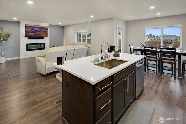 kitchen featuring dishwasher, a large fireplace, dark wood-type flooring, and a sink