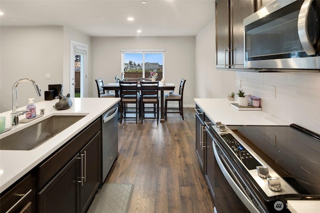 kitchen with dark wood-style floors, a sink, stainless steel appliances, light countertops, and tasteful backsplash