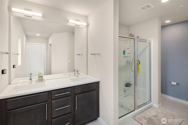 full bath featuring a sink, visible vents, a stall shower, and double vanity