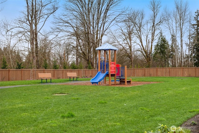 view of jungle gym with a lawn and fence