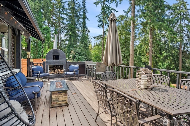 wooden deck featuring outdoor dining space, an outdoor fireplace, and an outdoor fire pit