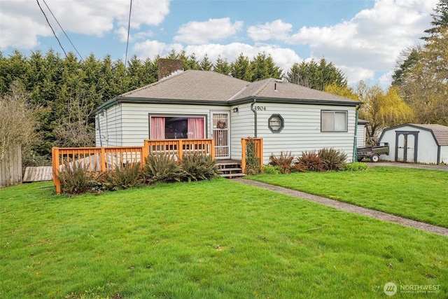 view of front of house with a storage unit, an outbuilding, a front yard, a wooden deck, and a chimney