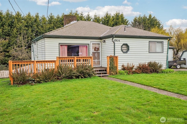 view of front of house with a front yard, a wooden deck, roof with shingles, and a chimney