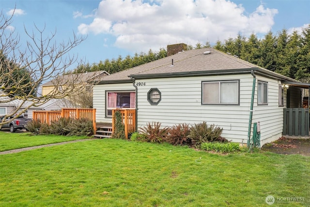 view of front of home featuring a wooden deck, a chimney, a front lawn, and a shingled roof