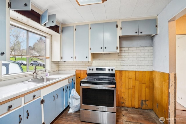 kitchen featuring dark wood finished floors, stainless steel electric stove, a sink, light countertops, and backsplash