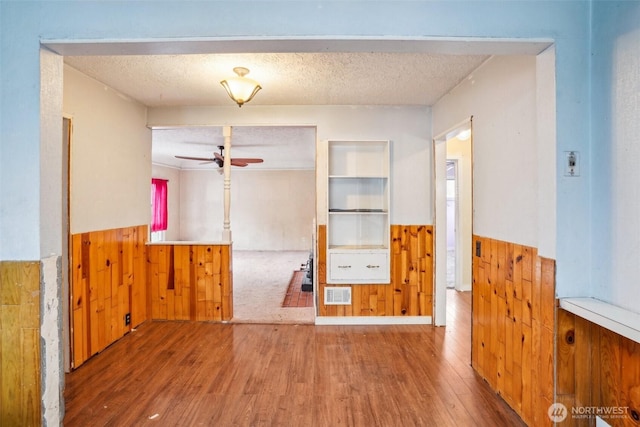 spare room with a wainscoted wall, wooden walls, visible vents, and a textured ceiling