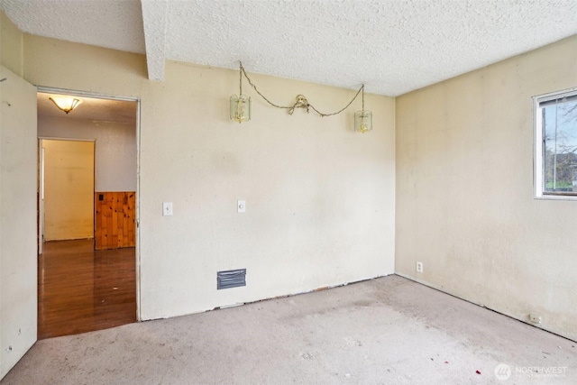 empty room featuring carpet flooring, visible vents, and a textured ceiling