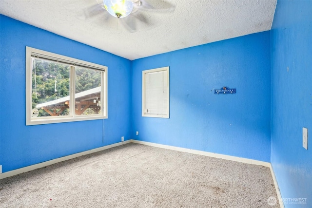 carpeted spare room with baseboards, a textured ceiling, and ceiling fan