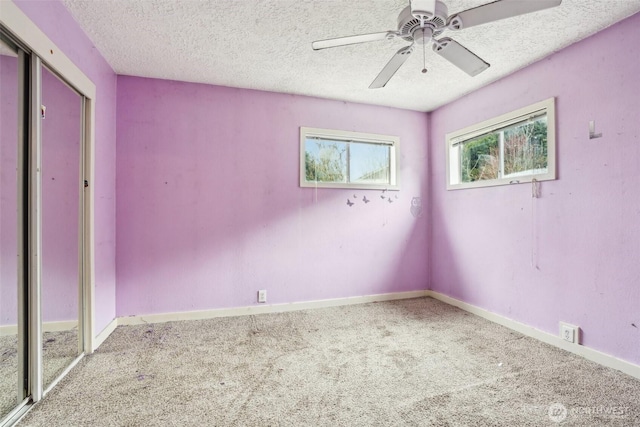 unfurnished bedroom featuring a ceiling fan, carpet, baseboards, a closet, and a textured ceiling