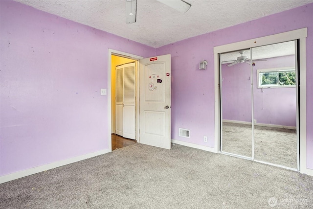 unfurnished bedroom featuring baseboards, visible vents, a textured ceiling, and carpet