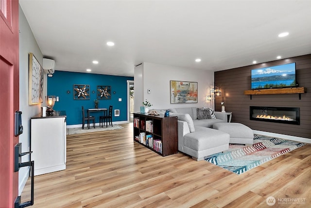 living room featuring light wood-style flooring, recessed lighting, baseboards, and a large fireplace