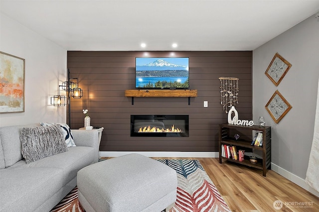 living room featuring light wood-style flooring, recessed lighting, baseboards, and a large fireplace