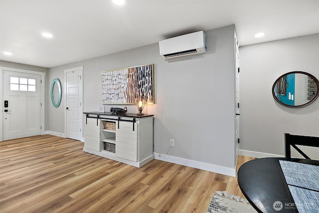 entrance foyer with an AC wall unit, light wood-type flooring, and baseboards