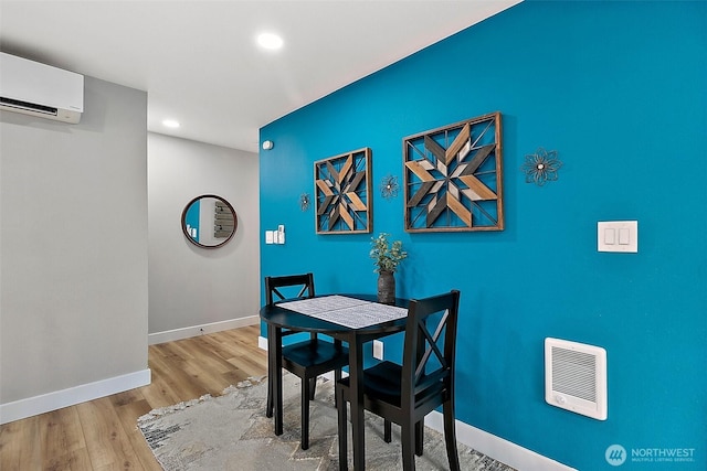 dining room featuring a wall mounted air conditioner, baseboards, wood finished floors, and recessed lighting