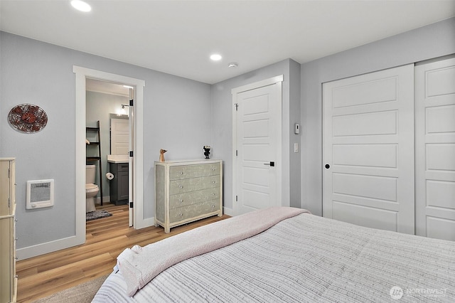 bedroom featuring heating unit, recessed lighting, a closet, light wood finished floors, and baseboards